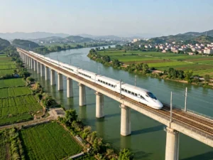 White high-speed train crossing a concrete viaduct above a green river valley